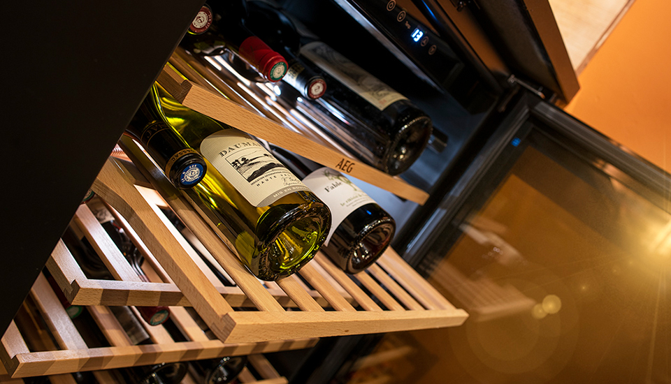 Bouteilles de vin disposées sur des étagères en bois dans une cave à vin avec affichage numérique.