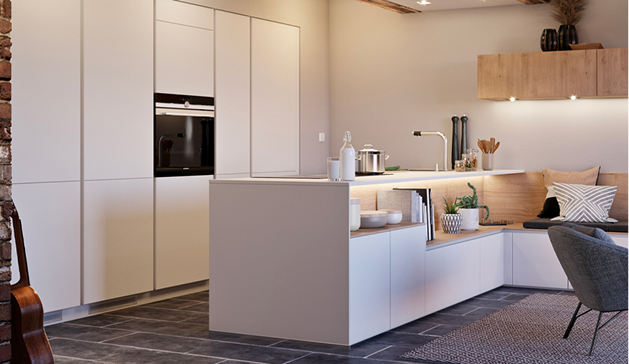 Cuisine moderne avec îlot central blanc, armoires intégrées, canapé gris, et décoration minimaliste sur étagères en bois clair.