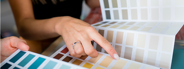 Une main pointe vers un nuancier de couleurs variées, allant des teintes bleues aux nuances beiges et grises.