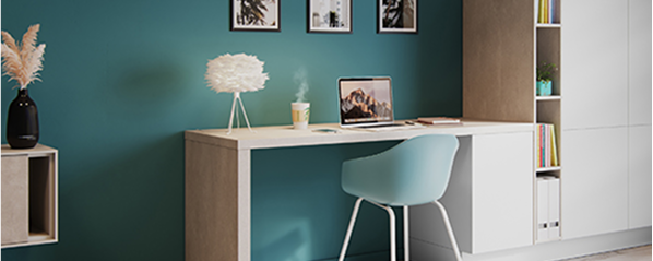 Un bureau moderne avec une chaise bleue, un ordinateur portable, une lampe blanche et des étagères remplies de livres sur un mur bleu.