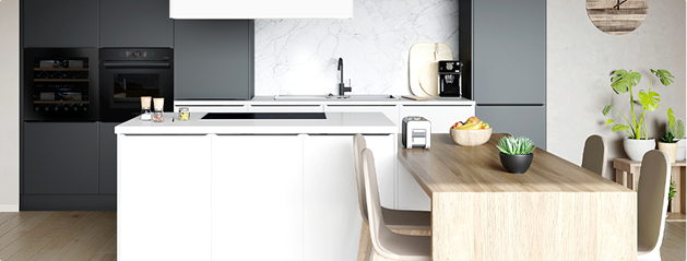 Cuisine moderne avec armoires grises, îlot central blanc, table en bois clair, et plantes vertes décoratives.