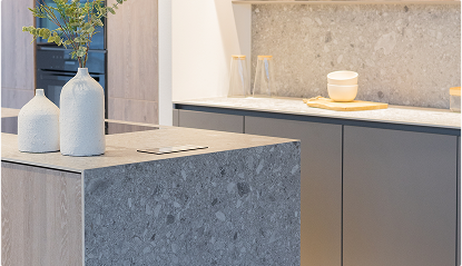 Deux vases blancs sur un îlot de cuisine en pierre grise, avec comptoirs gris et accessoires en bois clair en arrière-plan.