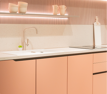 Cuisine moderne avec des placards roses, un plan de travail blanc, un évier, une étagère avec des tasses et un dosseret texturé.