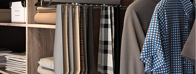 Chemises à motifs suspendues à côté de cravates et étagères avec vêtements pliés dans un placard en bois.