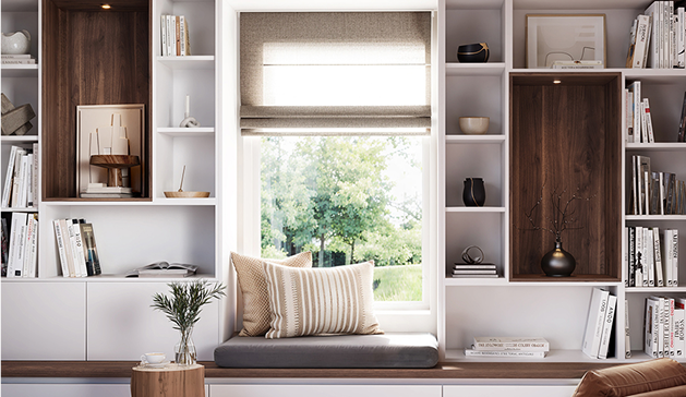 Espace de lecture avec coussins rayés sur un banc gris, entouré d'étagères blanches garnies de livres et d'objets décoratifs.