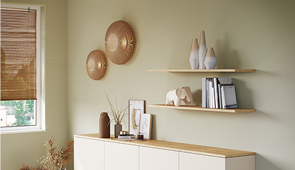 Deux étagères en bois avec vases et livres sont fixées sur un mur vert clair, à côté d'une fenêtre et d'un buffet blanc.