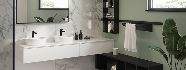 Deux lavabos blancs avec robinets noirs sur un meuble de salle de bains blanc, entourés de plantes vertes et de finitions en marbre.