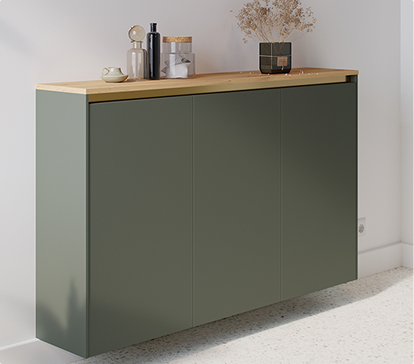 Un buffet vert avec plateau en bois clair, décoré de bouteilles, d'une tasse et d'un vase avec des fleurs séchées, sur un sol clair.