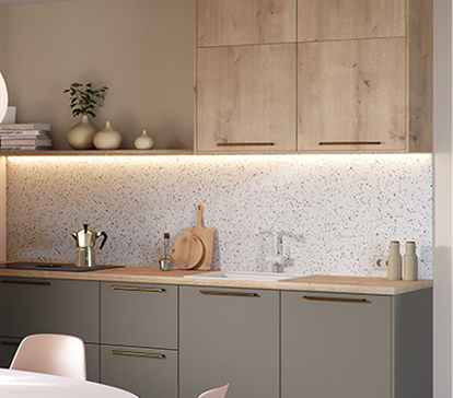 Cuisine moderne avec placards en bois clair, plan de travail beige, crédence en terrazzo, cafetière en inox et vaisselle décorative.